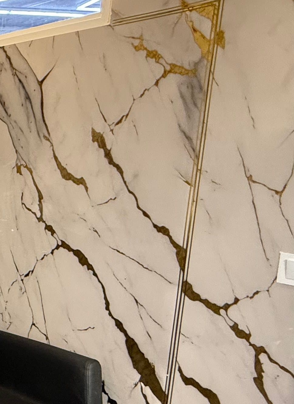 Détail d'un mur en marbre blanc veiné d'or, souligné d'un double filet doré
