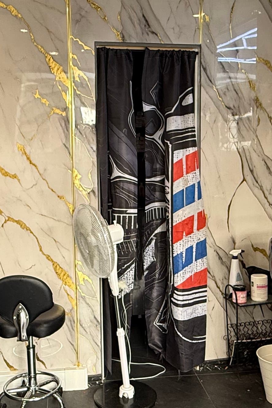 Rideau de porte imprimé d'un poteau de barbier bleu, blanc et rouge, entre deux murs de marbre
