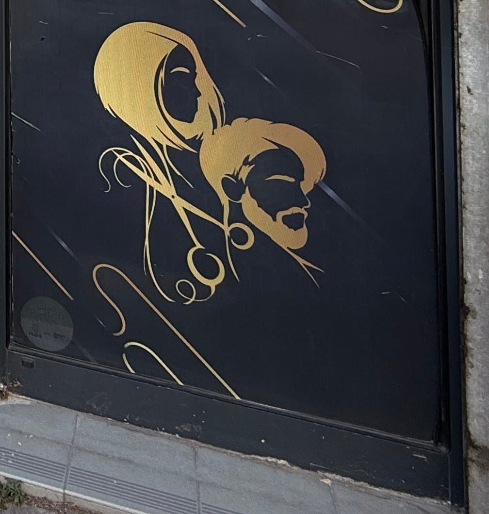 Détail de la porte d'entrée : silhouettes dorées d'une femme et d'un homme, avec des ciseaux