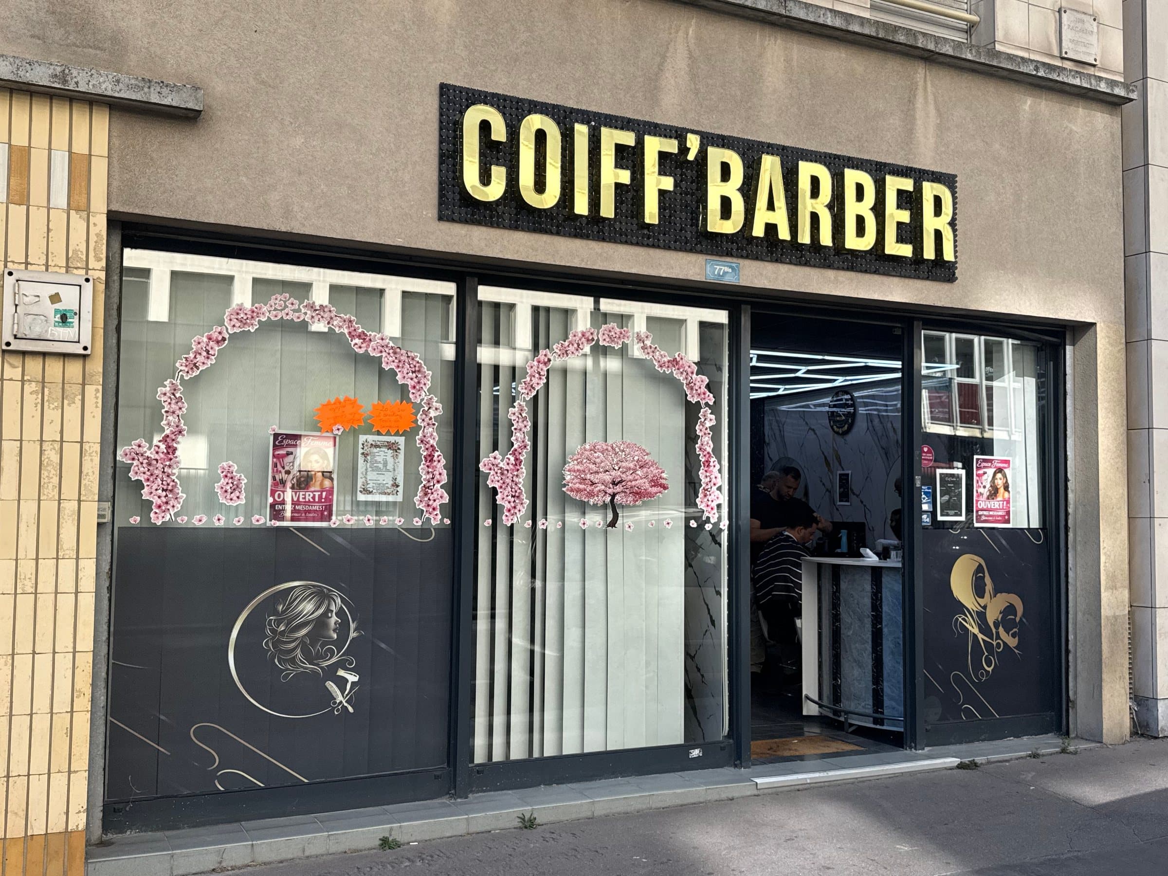 La façade de face : enseigne dorée, arches fleuries et silhouettes dorées sur la vitrine