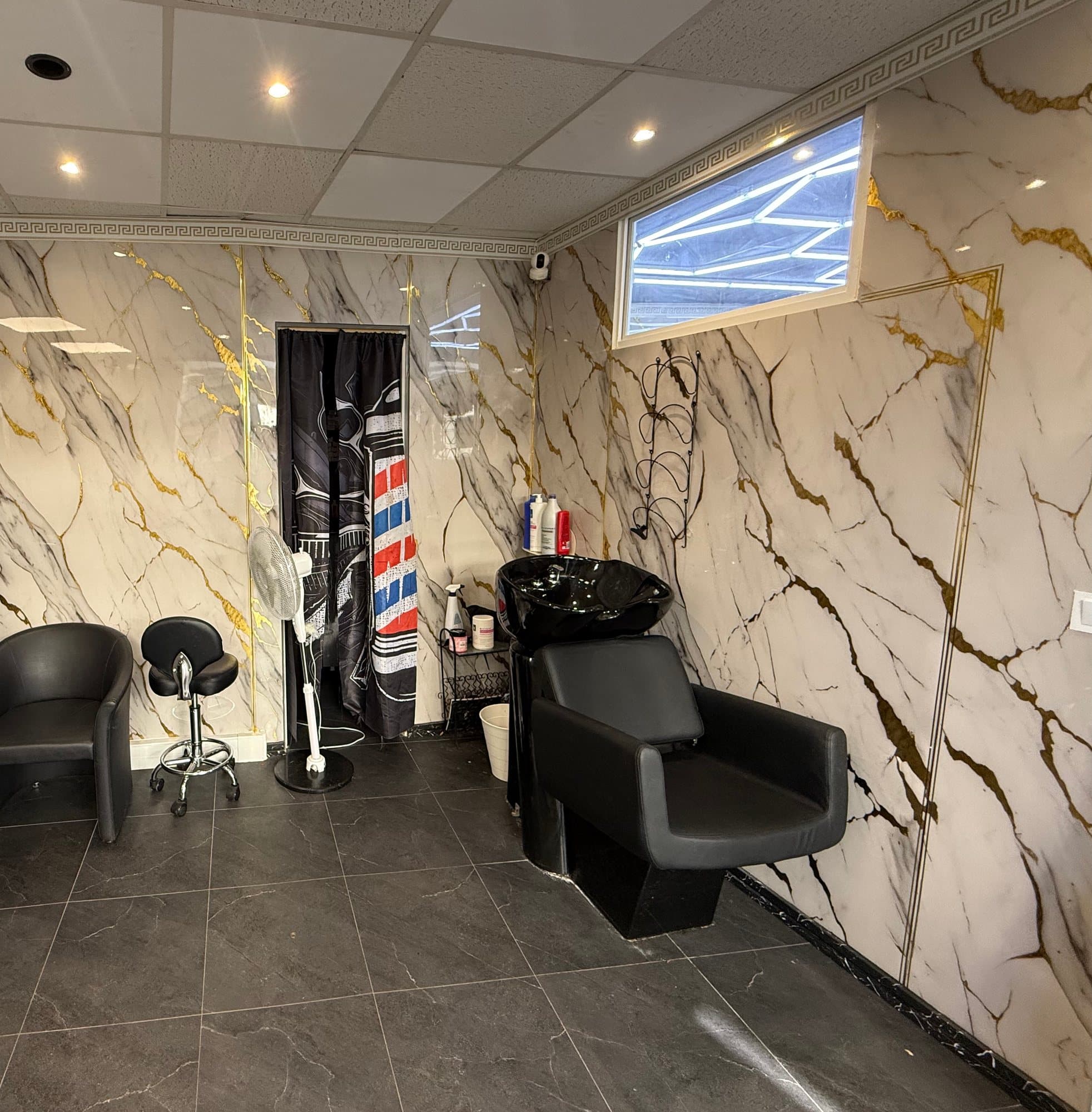 Le bac à shampoing de l'Espace Femme, devant un mur de marbre veiné d'or