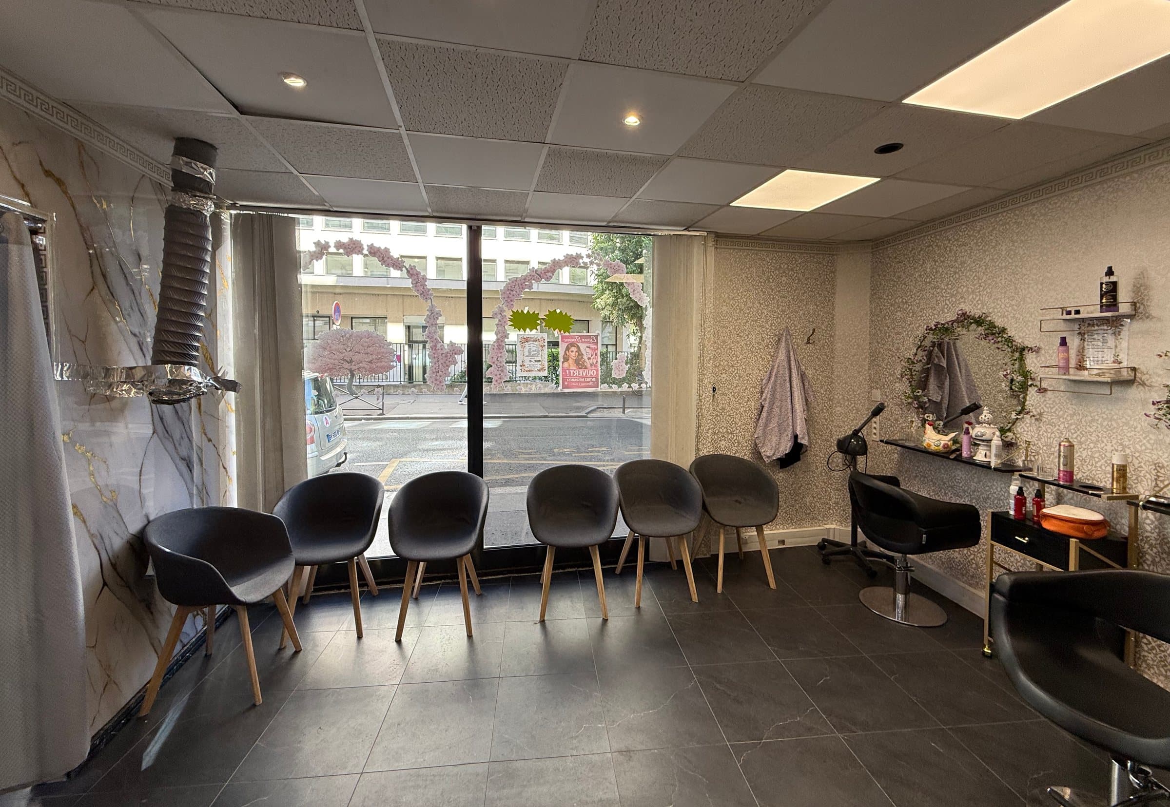 Espace Femme : fauteuils d'attente face à la vitrine décorée d'arches de fleurs de cerisier, poste de coiffure au miroir fleuri